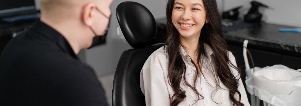Two people in an office setting, one wearing black shirt facing away, the other smiling woman in white shirt facing camera.