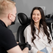 Two people in an office setting, one wearing black shirt facing away, the other smiling woman in white shirt facing camera.