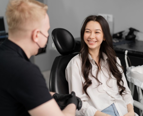 Two people in an office setting, one wearing black shirt facing away, the other smiling woman in white shirt facing camera.
