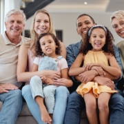 Happy multi-generational family smiling together on couch, representing pediatric and adult dental care.