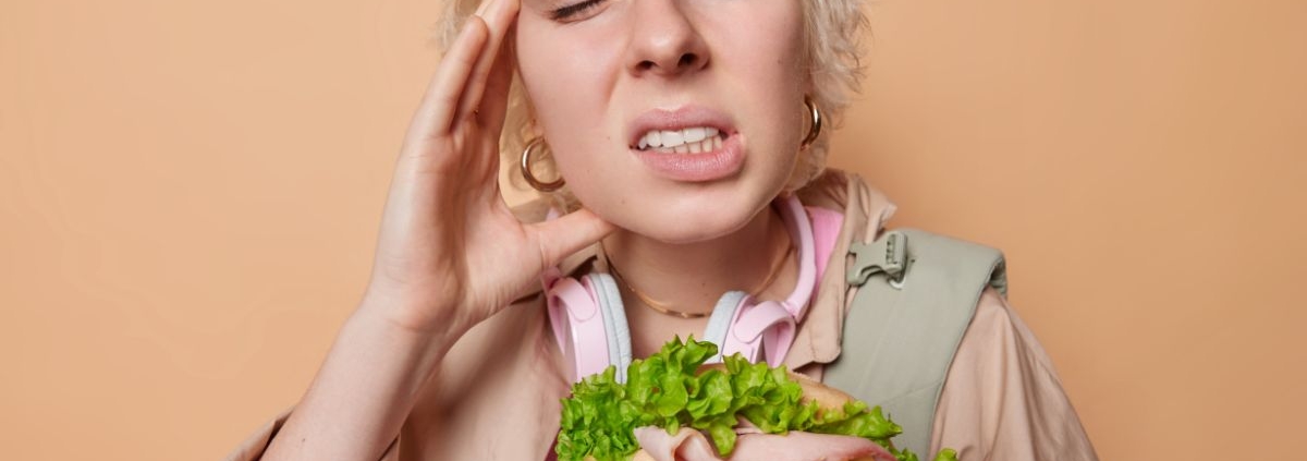 Child experiencing tooth pain while eating a sandwich, illustrating dental emergencies.
