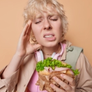 Child experiencing tooth pain while eating a sandwich, illustrating dental emergencies.