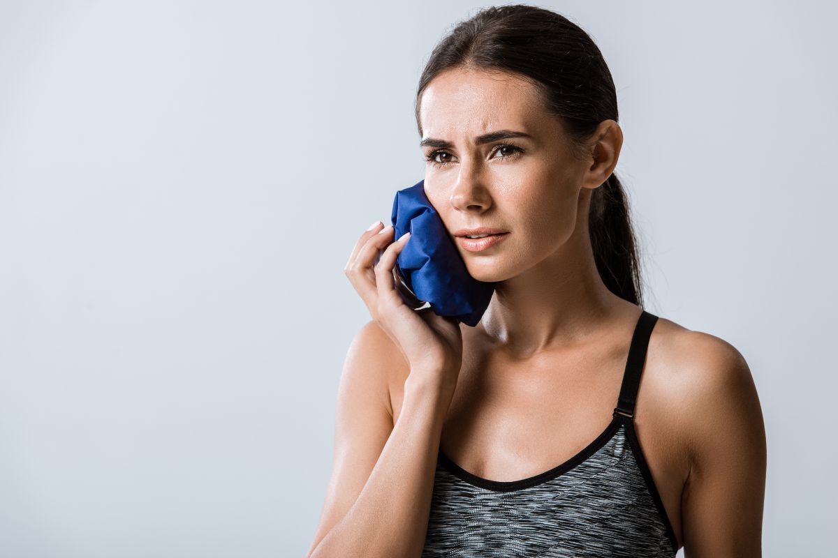 Applying a cold compress to relieve severe tooth pain before visiting a dentist