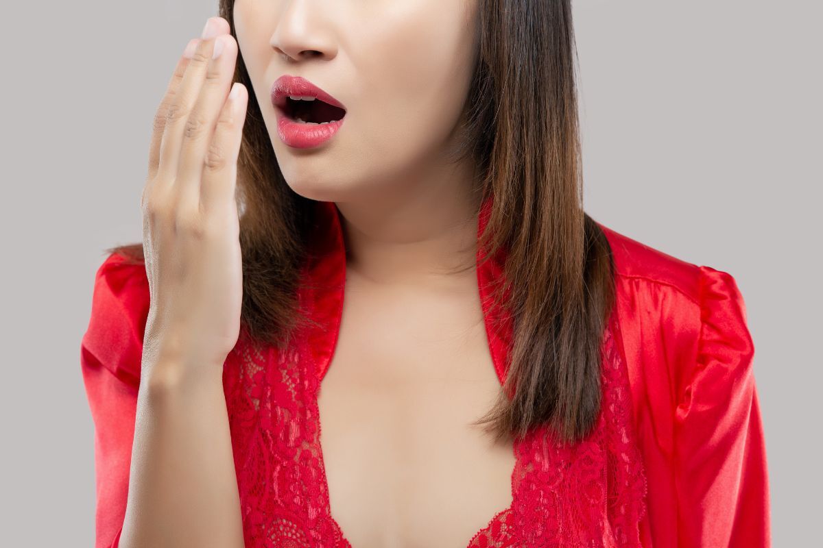 A woman checks her breath with concern, illustrating how persistent bad breath may be a sign of underlying oral health issues that should be evaluated by a dental professional.