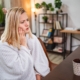 Woman with toothache holding her cheek in pain at her desk, experiencing dental discomfort.