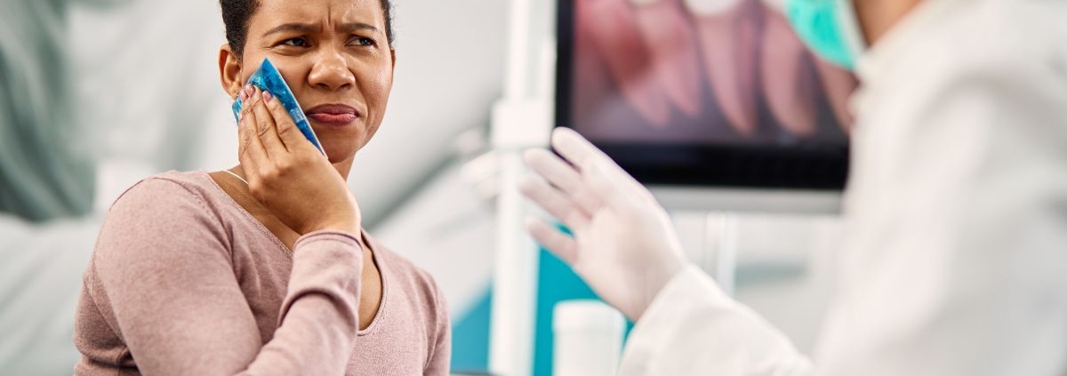 Patient holding cheek in pain during dental consultation with dentist in Jacksonville, NC office.