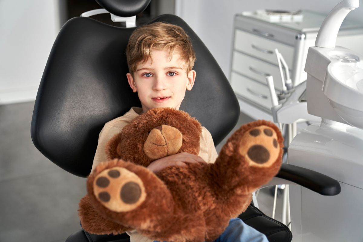 Child preparing for a first dental visit by practicing a dental checkup with a favorite toy