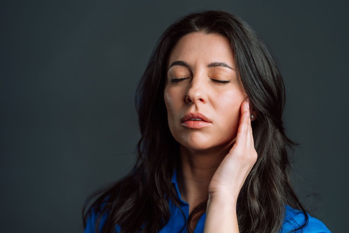 Woman holding her jaw in pain, illustrating severe toothache symptoms that may require emergency dental treatment and prompt professional care.
