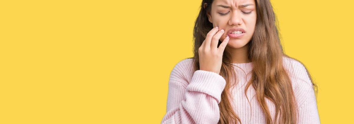 Woman with tooth pain touching her cheek, showing gum disease symptoms.