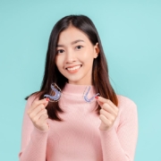 Woman holding two clear retainers after finishing Invisalign treatment