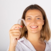 Woman holding a clear Invisalign aligner while demonstrating transparent orthodontic treatment.